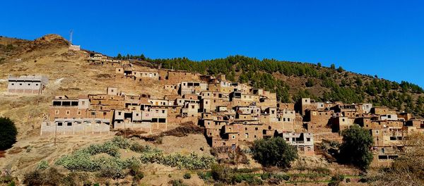 Low angle view of houses on mountain against clear blue sky