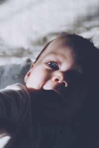 High angle portrait of cute girl lying on bed at home