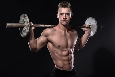 Portrait of shirtless muscular man exercising in gym