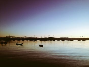 Boats in calm sea against clear sky