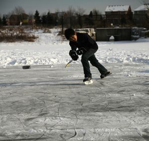 Full length of boy ice skating on frozen lake during winter
