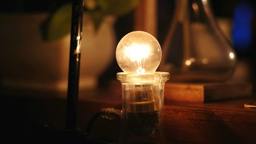 Close-up of illuminated light bulb on table