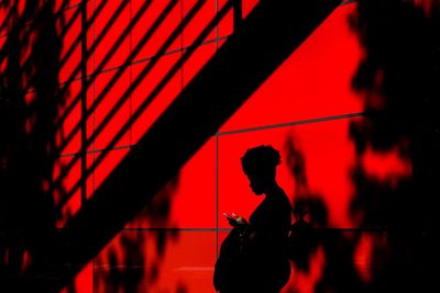 Silhouette of woman standing by wall