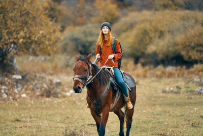 Portrait of young woman riding horse on land