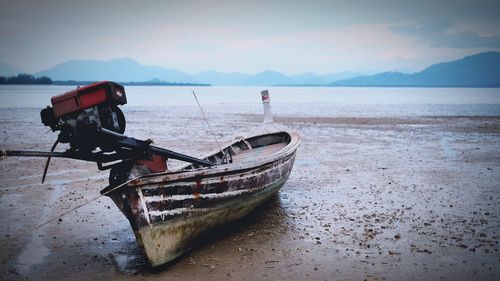 Boat moored on beach against sky