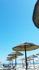 Scenic view of tourist on beach resting under umbrella against clear sky