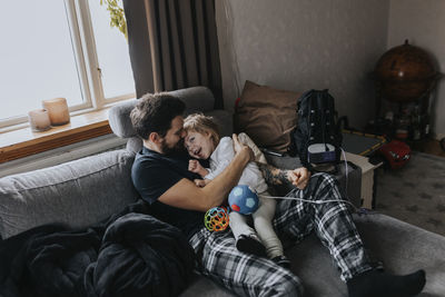 Father hugging disabled child on sofa