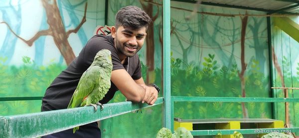 Young man and parrot looking at each other...