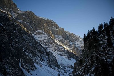 Low angle view of snowcapped mountains against clear sky