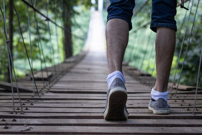 Low section of man standing on footbridge