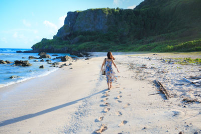 Woman walking on beach against sky