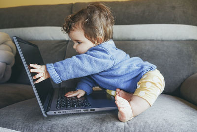 Rear view of man using mobile phone while sitting on sofa