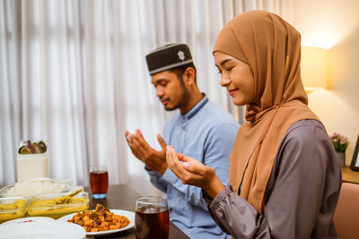 Couple praying while having food at home