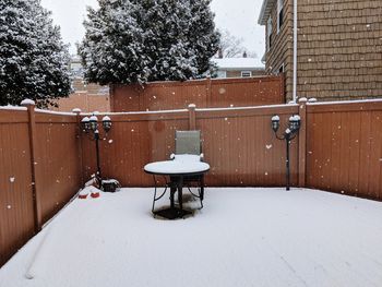 Empty benches on snow covered field by building