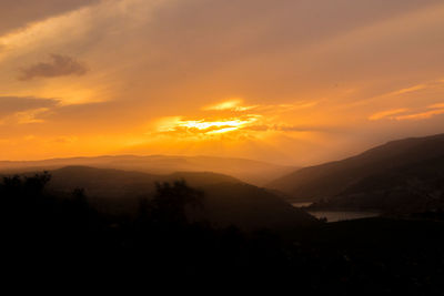 Scenic view of silhouette mountains against orange sky