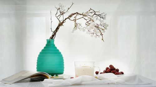 Food and drink by white flowers on table at home