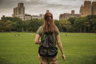 Rear view of woman with backpack standing on field