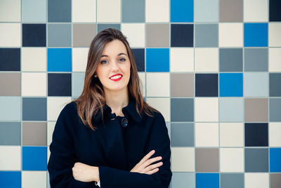 Portrait of a smiling young woman against wall