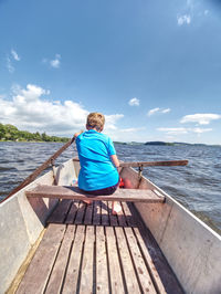 Boy in blue with life jackets at legs floats on vessel boat and hard working. young man sail on lake