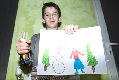 Portrait of smiling boy holding paper outdoors