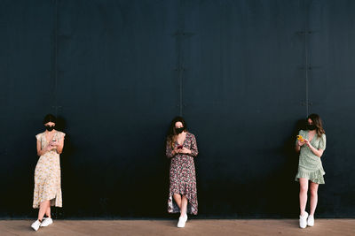 Rear view of women standing against wall