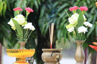Incenses amidst flower vase outside temple