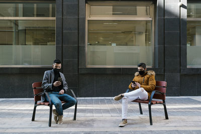 Man sitting on seat against glass window