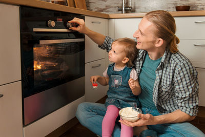 Father and kid waiting for freshly baked buns bread, cinnabons or pastry near the oven happy time