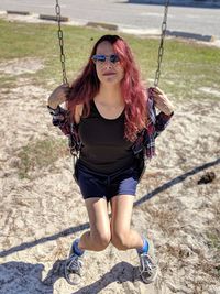 Portrait of young woman sitting on swing