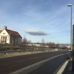 Empty road by buildings against sky