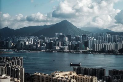 City at waterfront against cloudy sky