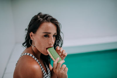 Portrait of woman holding ice cream against sea