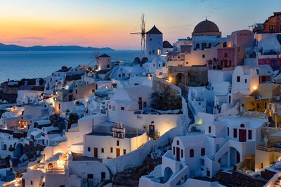 High angle view of townscape by sea against sky during sunset