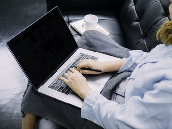 Midsection of businesswoman using laptop while sitting on sofa