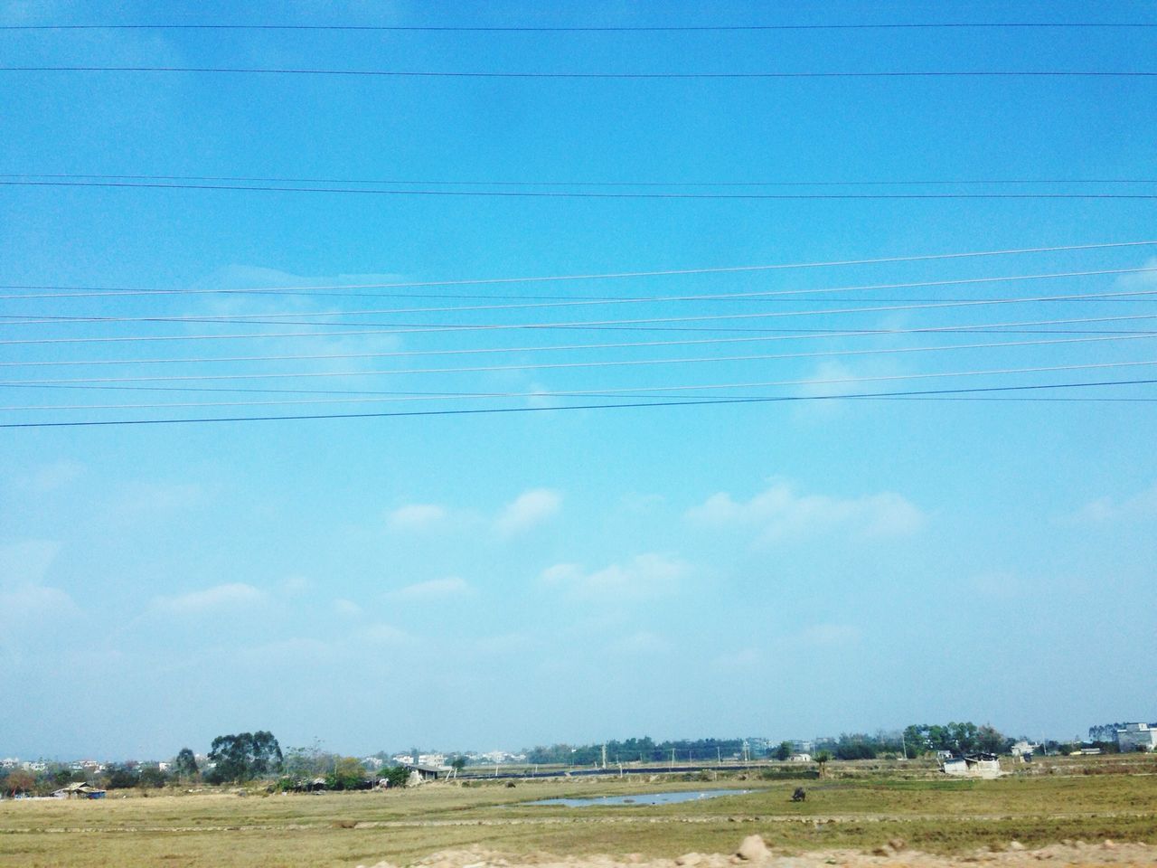 blue, field, landscape, grass, sky, rural scene, transportation, built structure, clear sky, tranquil scene, tranquility, nature, copy space, building exterior, architecture, tree, road, day, outdoors, agriculture