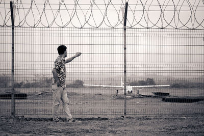 Rear view of boy standing by fence