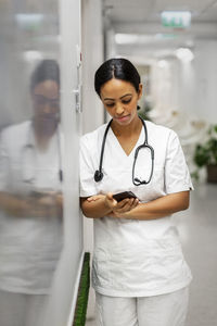 Female doctor using cell phone at corridor
