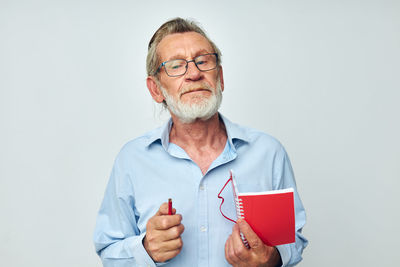 Portrait of senior man holding paper currency against white background