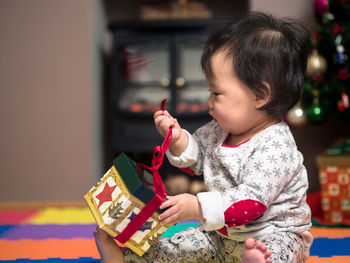 Close-up of baby girl unwrapping christmas gift