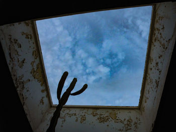 Low angle view of rusty window against sky