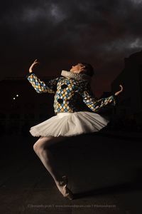 Rear view of woman dancing against sky at night