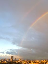 Rainbow over city against sky