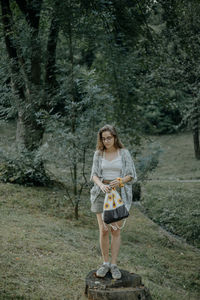 Full length of young woman standing in forest