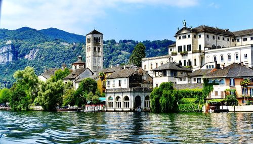 Buildings by river against sky