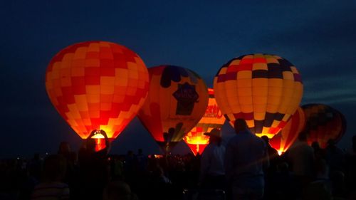 People on hot air balloon against sky at night