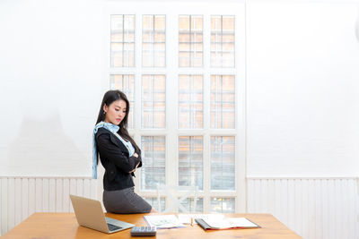 Full length of woman sitting on table at home