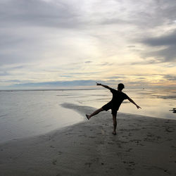 Full length of man on beach against sky during sunset