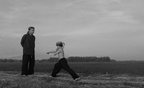 Man looking at son practicing martial arts on field