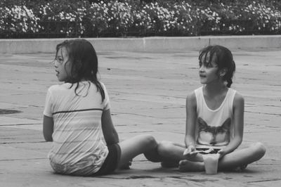 Siblings having food while sitting on shore at beach