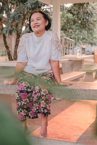 Portrait of smiling young woman standing against plants